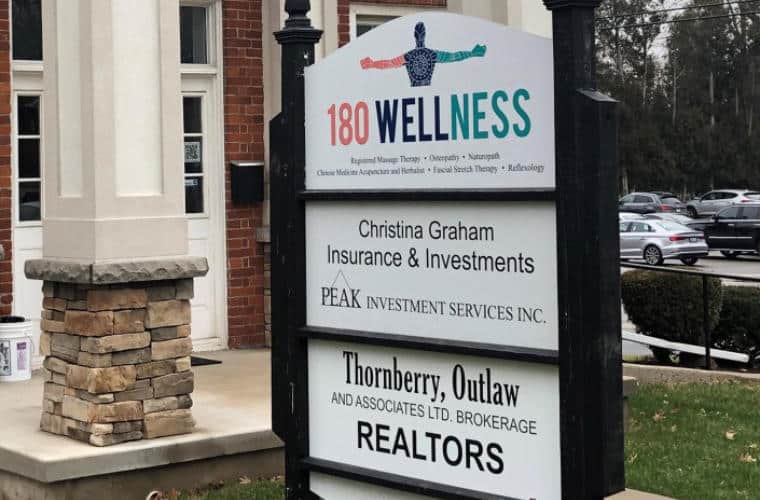 A pylon sign in front of a building with 180 Wellness on it.