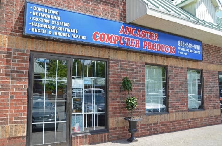 A red brick building with large windows and a sign for Ancaster Computer Products above the entrance.