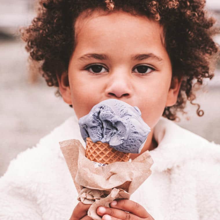 A young girl with curly hair eating ice cream.