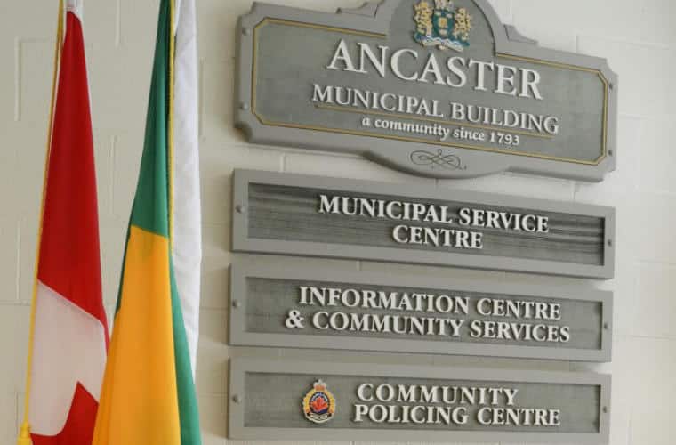 A plaque for Ancaster Municipal Building on a white brick wall.