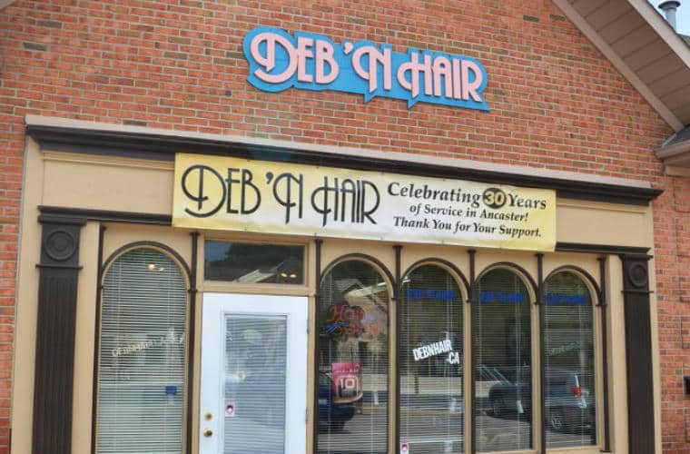 A red brick building with arched windows on the first floor and a sign for Deb 'n' Hair above them.