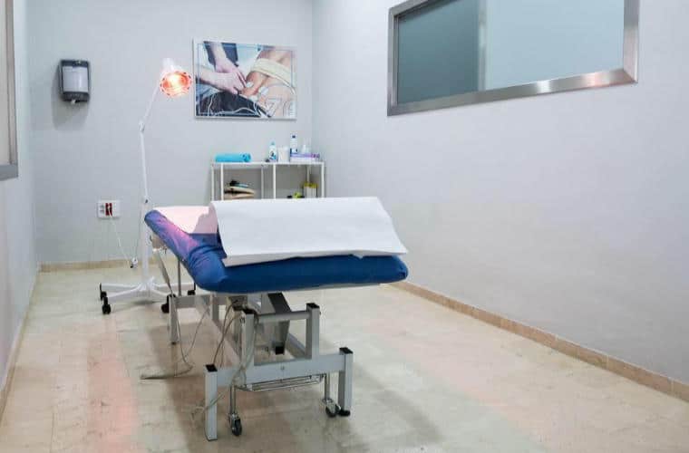A white room with a physiotherapy bed in the middle.