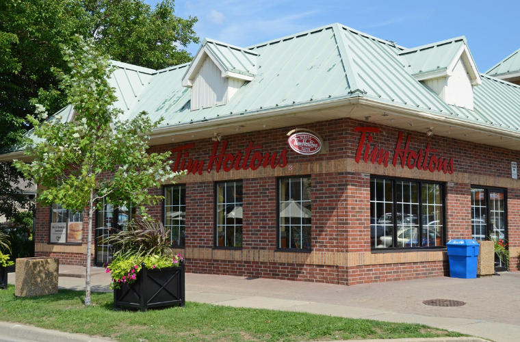 A red brick Tim Hortons with a light green roof.